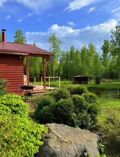 a cabin with a deck and a picnic table and a pond at Meiranu krasts in Bērzgale