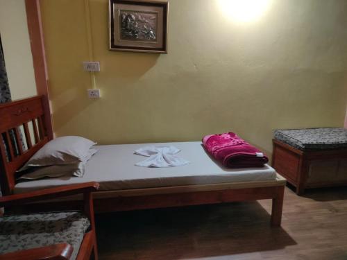 a small bedroom with a bed with pink sheets at Hillside Highway Cottages in Shillong