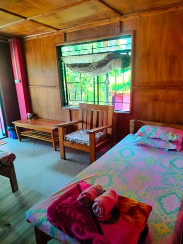 a bedroom with a bed and a chair and a window at Hillside Highway Cottages in Shillong