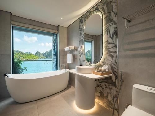 a bathroom with a tub and a sink and a mirror at Azura Cruise in Ha Long