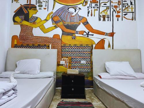 two beds in a room with a mural on the wall at Jana Pyramids view inn in Cairo