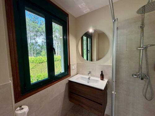 a bathroom with a sink and a window and a shower at Hostal Finca La Oliva in Oleiros