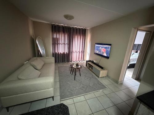 a living room with a white couch and a tv at Malwandla 1bed full apartment in Centurion