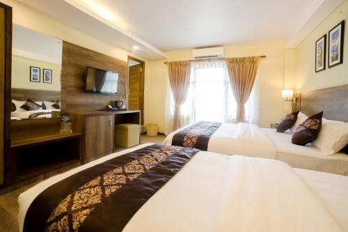 a hotel room with two beds and a television at Hotel Thakali Inn in Kathmandu