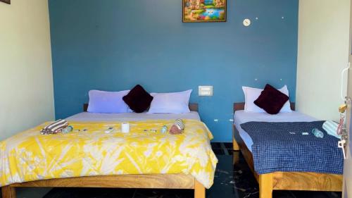 a bedroom with two beds and a blue wall at Khushi Homestay Hampi in New Hampi