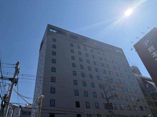 a tall white building with the sun in the sky at HOTEL AMANEK Kumamoto in Kumamoto