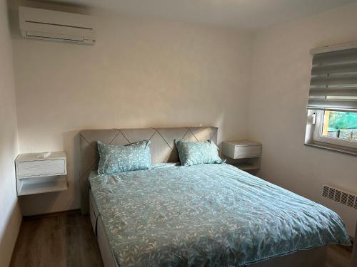a bedroom with a bed with blue sheets and a window at Sarajevo Villa Oasis in Doglodi
