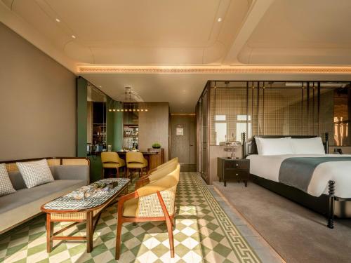 a hotel room with a bed and a couch and a table at Xiamen Lujiang Harbourview Hotel-panoramic sea views over Gulangyu in Xiamen