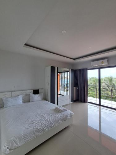a bedroom with a white bed and a large window at Sleek Modern Studio in Rawai, Phuket in Ban Saiyuan (1)
