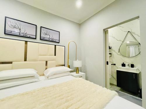 a white bedroom with a bed and a mirror at Cozy and Warm-Private Queen Bedroom with Private Bathroom & shared Kitchen& Lounge in Parklands