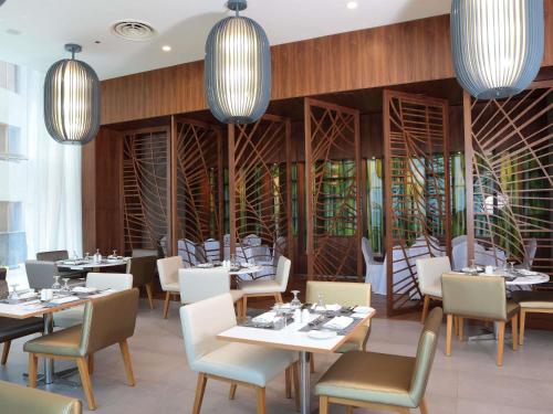 a dining room with tables and chairs and chandeliers at Novotel Jazan in Jazan