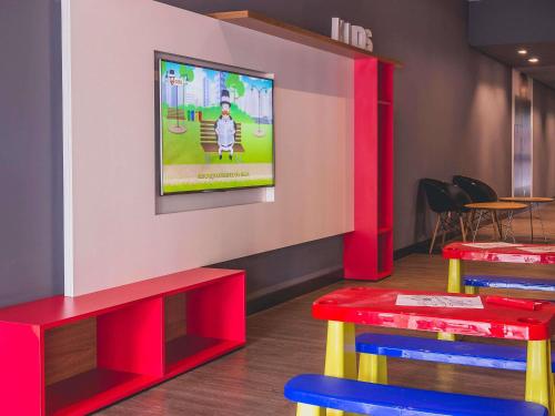 a waiting room with two tables and a tv on the wall at ibis Carlos Barbosa in Carlos Barbosa
