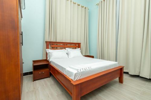 a bedroom with a bed with white sheets and white pillows at Akibo Residency Apartment in Mwanza