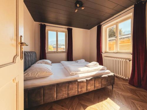 a bed in a room with two windows at Doras Ferienhaus in Bad Reichenhall