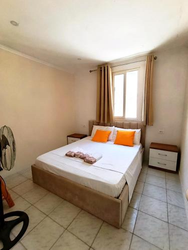a bedroom with a bed with orange pillows and a window at TE Shkodrant 1 in Baks-Rrjoll