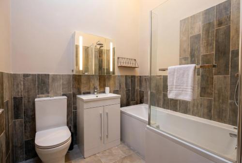 a bathroom with a toilet and a tub and a sink at Lynwood Barn - Barn Conversion in Midsomer Norton, Parking & Dog Friendly in Radstock