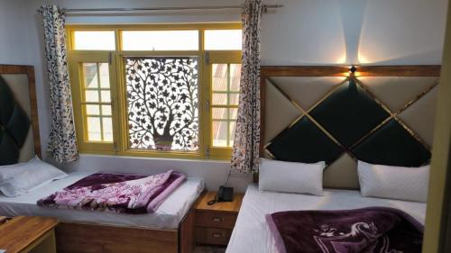 a bedroom with two beds and a window at Hotel green chinar & restaurant in Srinagar
