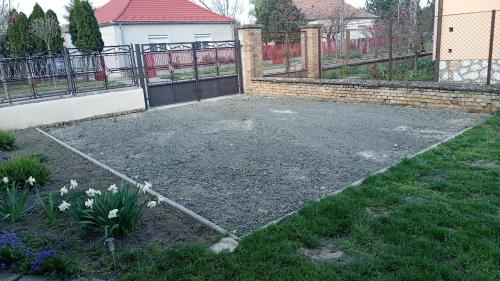 a garden with a driveway with a fence and flowers at Neubauer Vendégház*** Mohács in Mohács