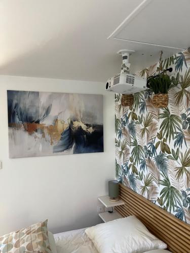 a bedroom with a bed and a painting on the wall at La maisonnette de chez Pascalou in Lège-Cap-Ferret