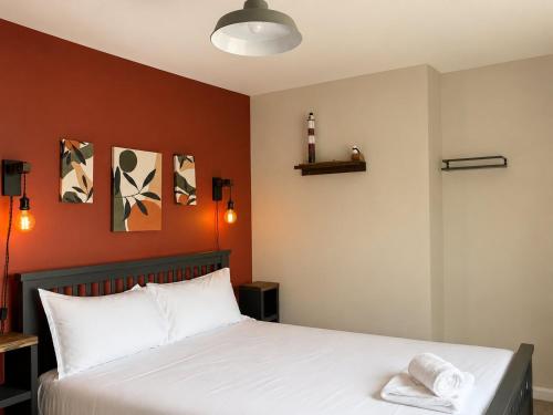 a bedroom with a white bed with orange walls at Llantarnam House by Tŷ SA in Cardiff