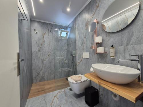 a bathroom with a sink and a toilet and a mirror at Sigma Hotel in Paralia Vrachou