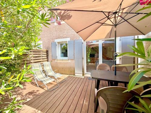 a wooden deck with a table and chairs and an umbrella at La cachette du Mas, 4 pers Piscine à Calvisson in Calvisson