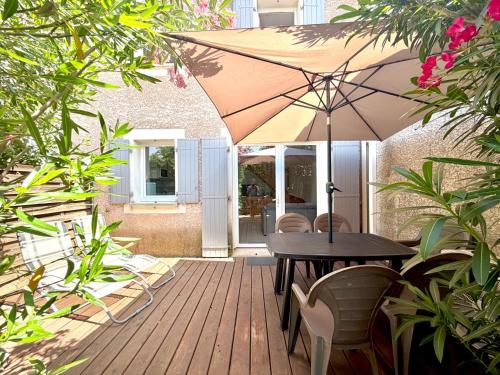 a wooden deck with a table and an umbrella at La cachette du Mas, 4 pers Piscine à Calvisson in Calvisson