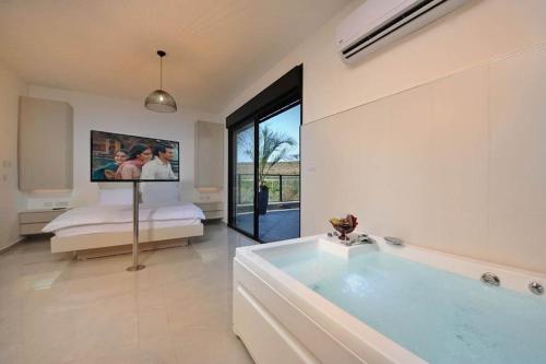 a large bathroom with a tub and a bedroom at קולינה וארדה in ‘Amqa