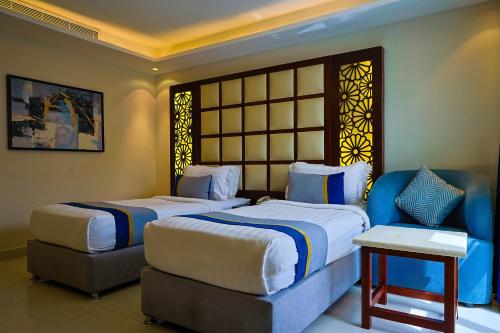 a hotel room with two beds and a chair at Al Muhaidb Al Olaya Suites - Economic in Riyadh