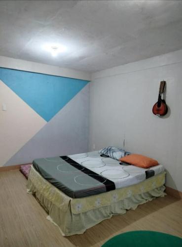 a bed in a room with a guitar on the wall at Gerry's Place in Iloilo City
