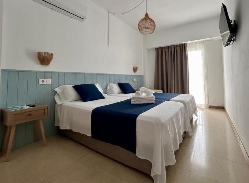 a bedroom with a large bed with blue and white sheets at Ca sa Madona Hostal in Paguera