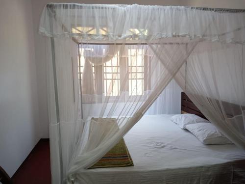 a bedroom with a canopy bed with a window at Green Gardens in Weligama