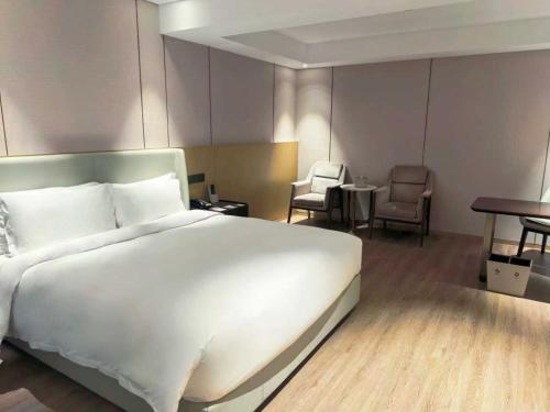 a bedroom with a large white bed and chairs at Wyndham Shanghai Pudong in Shanghai