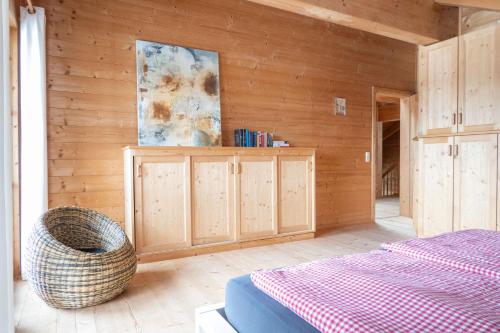 a bedroom with a bed and a wooden wall at Allgäu Holzhaus I Bergpanorama & Natur pur im Herzen des Allgäus! in Weitnau