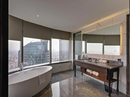 a bathroom with a tub and a large window at Mercure Jakarta Gatot Subroto in Jakarta