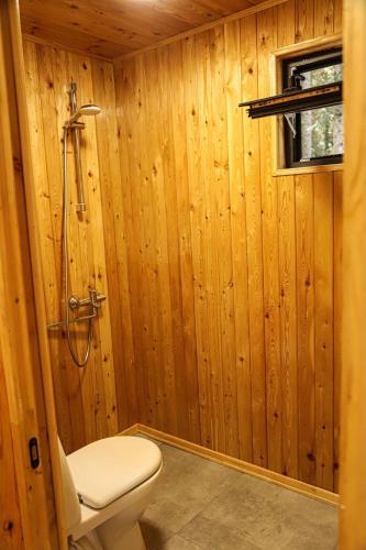 a wooden bathroom with a toilet and a shower at Rest House in Oni