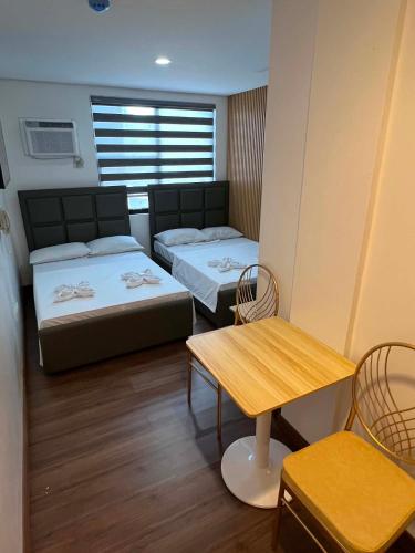 a room with two beds and a table and chairs at LUNA by LCB Apartelle and Resort Tagaytay in Tagaytay