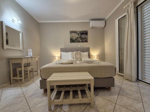 a bedroom with a bed with a table and a desk at Sigma Hotel in Paralia Vrachou