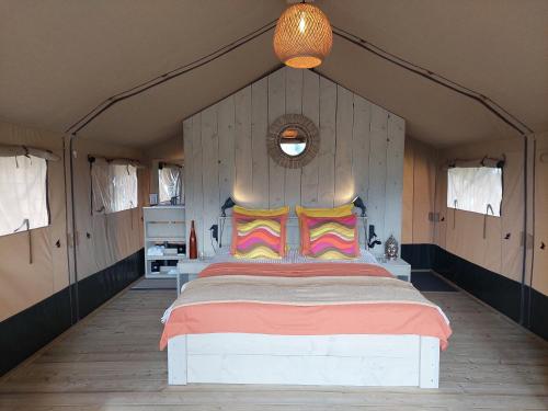 a bedroom with a large bed with colorful pillows at casa la luna glamping in Alhaurín el Grande