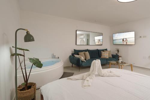 a white bedroom with a tub and a couch at קולינה וארדה in ‘Amqa