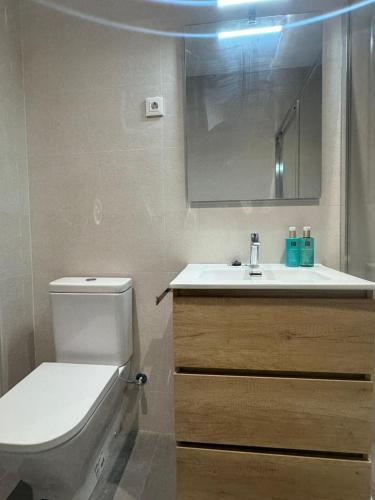 a bathroom with a toilet and a sink and a mirror at Set Blau Apartamentos in El Prat de Llobregat