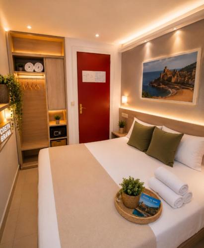 a bedroom with a large white bed with a basket of towels at St Jordi Hagdigadar Tossa in Tossa de Mar
