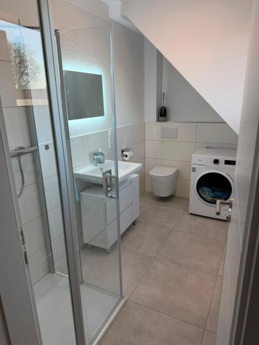 a bathroom with a shower and a sink and a washing machine at Haus Bahnhofsblick in Ottersberg