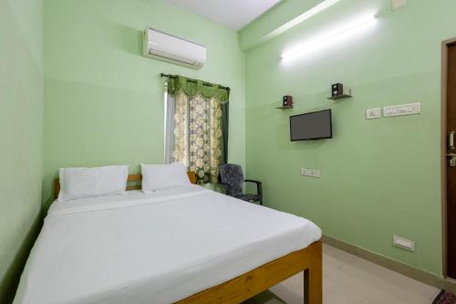 a bedroom with a white bed and a tv at Hotel Sridevi Grand in Vākalapūdi