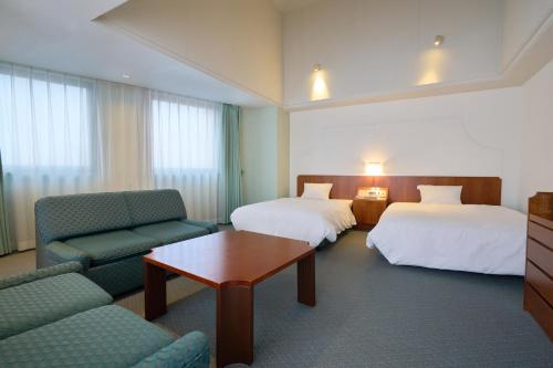 a hotel room with two beds and a couch and a table at hotel VERDE in Arao