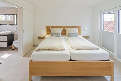 a bedroom with a large bed with white sheets at MeerBlau in Dornumersiel