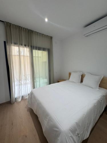 a white bed in a room with a large window at Set Blau Apartamentos in El Prat de Llobregat