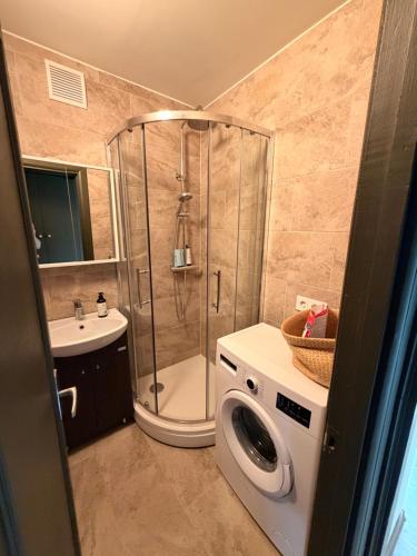 a bathroom with a shower and a washing machine at Kauguri apartment residence in Jūrmala