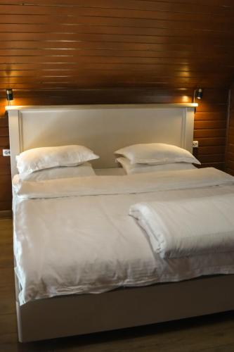a large white bed with white sheets and pillows at Kolsay Lake Cabins in Kurmenty