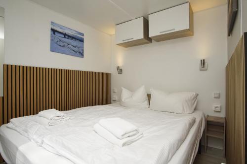 a white bed with two towels on top of it at Tiny Homes Nr 822 in Göhren
